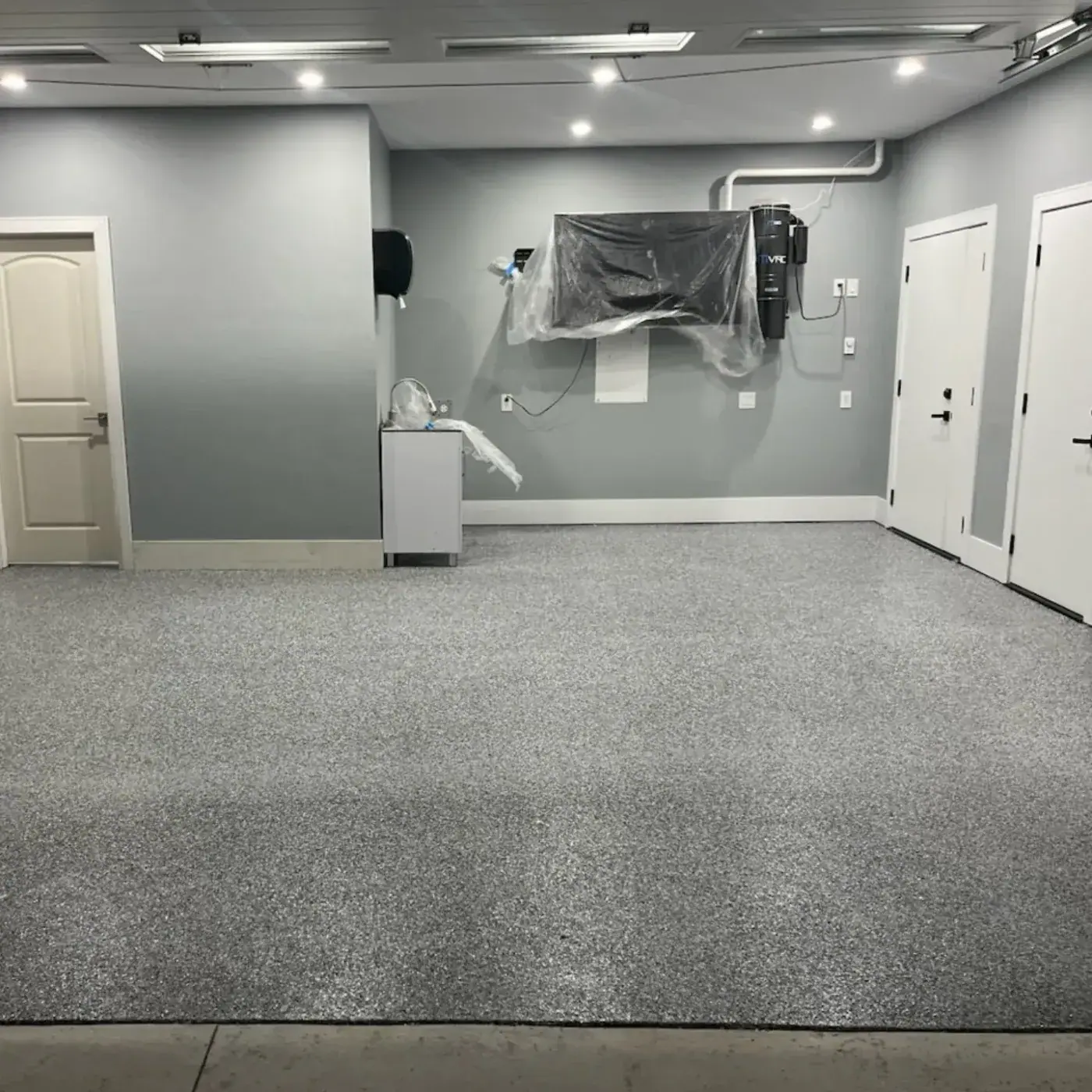 Double garage with grey painted walls and a light grey flake floor under recessed ceiling lights.