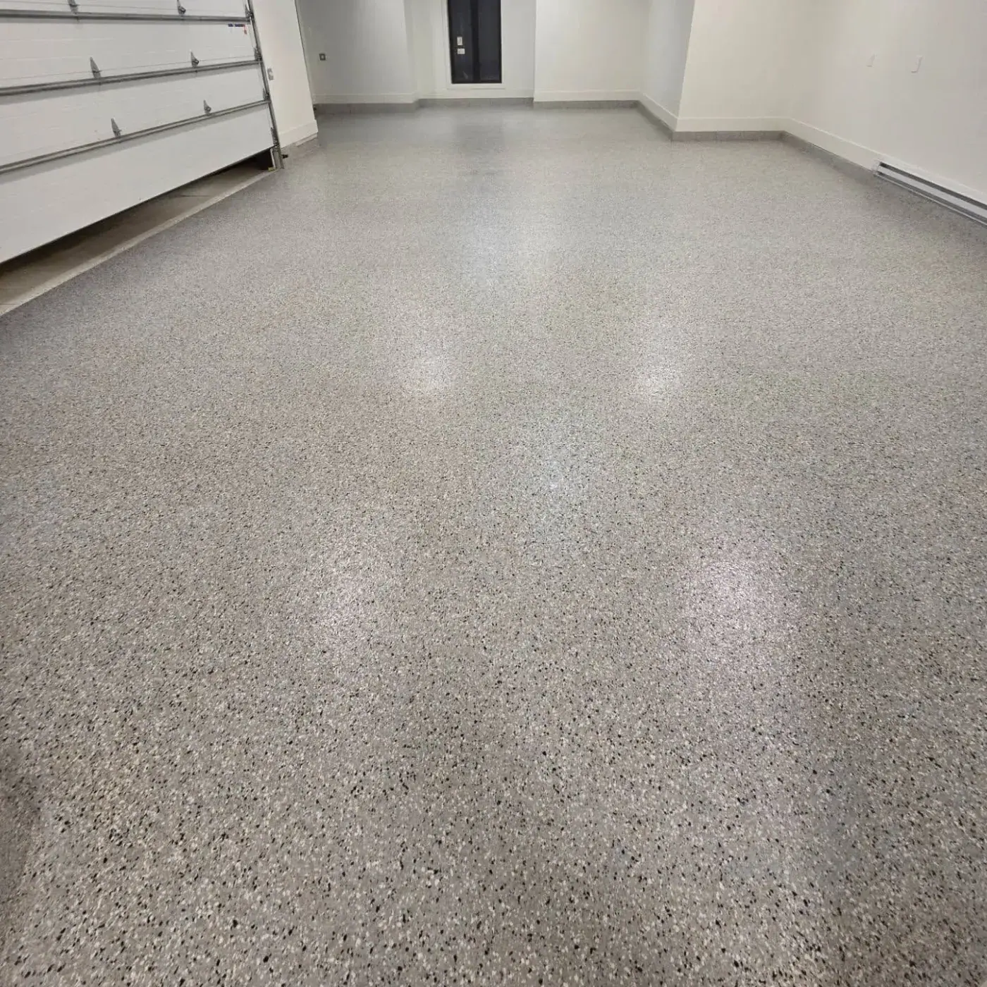 Garage bay with a white sectional door and a pale speckled flake floor finished to a satin sheen.