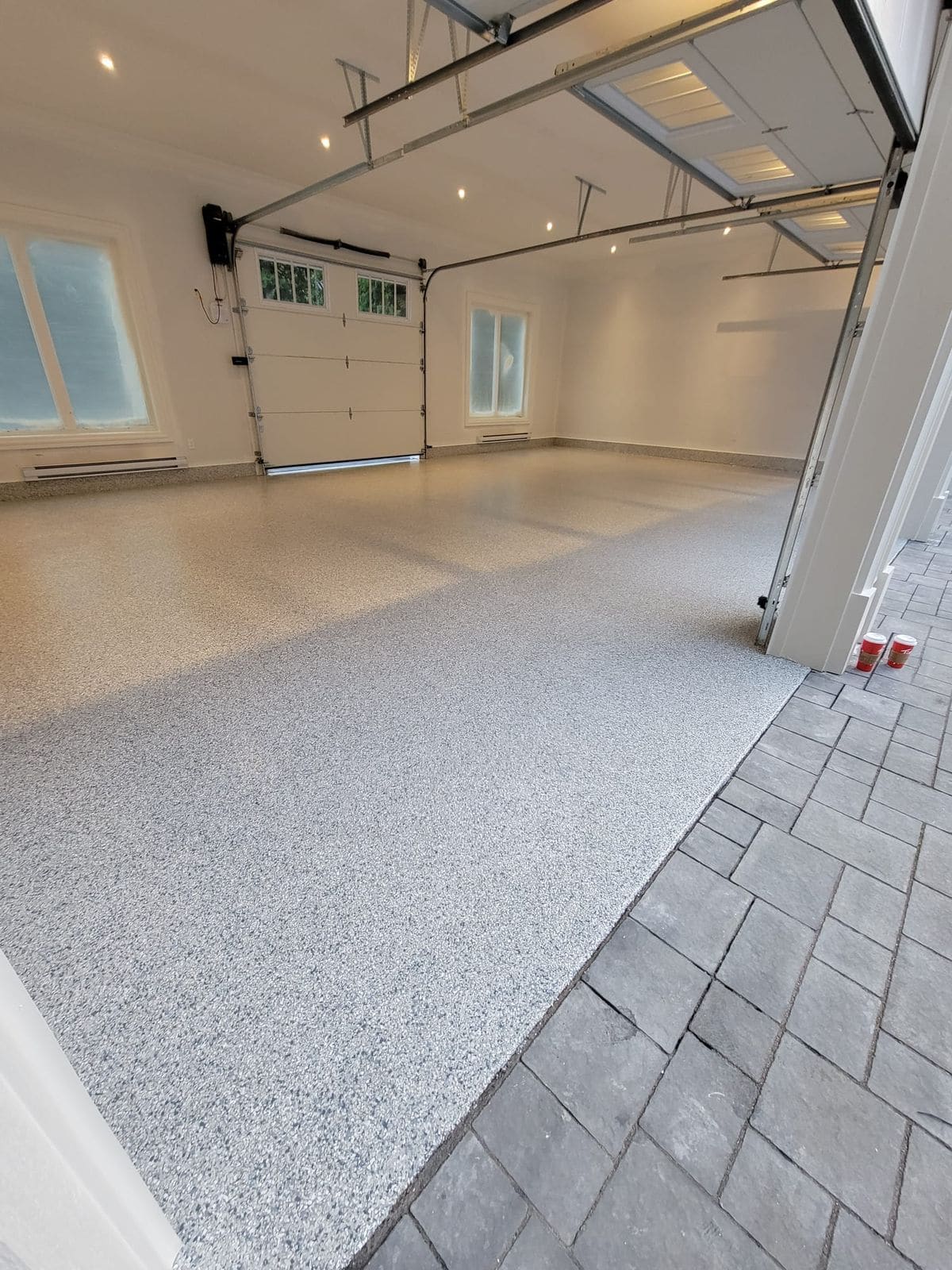 A garage floor finished in a grey and white flake epoxy coating